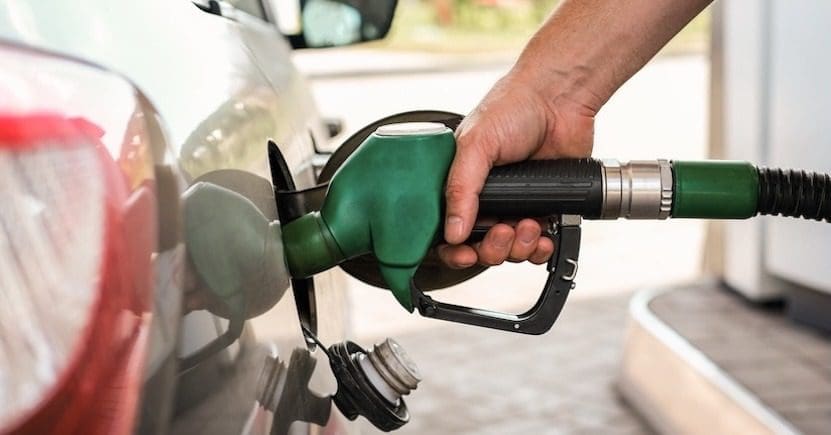 Close-up of a hand refueling a car with a green nozzle at a gas station